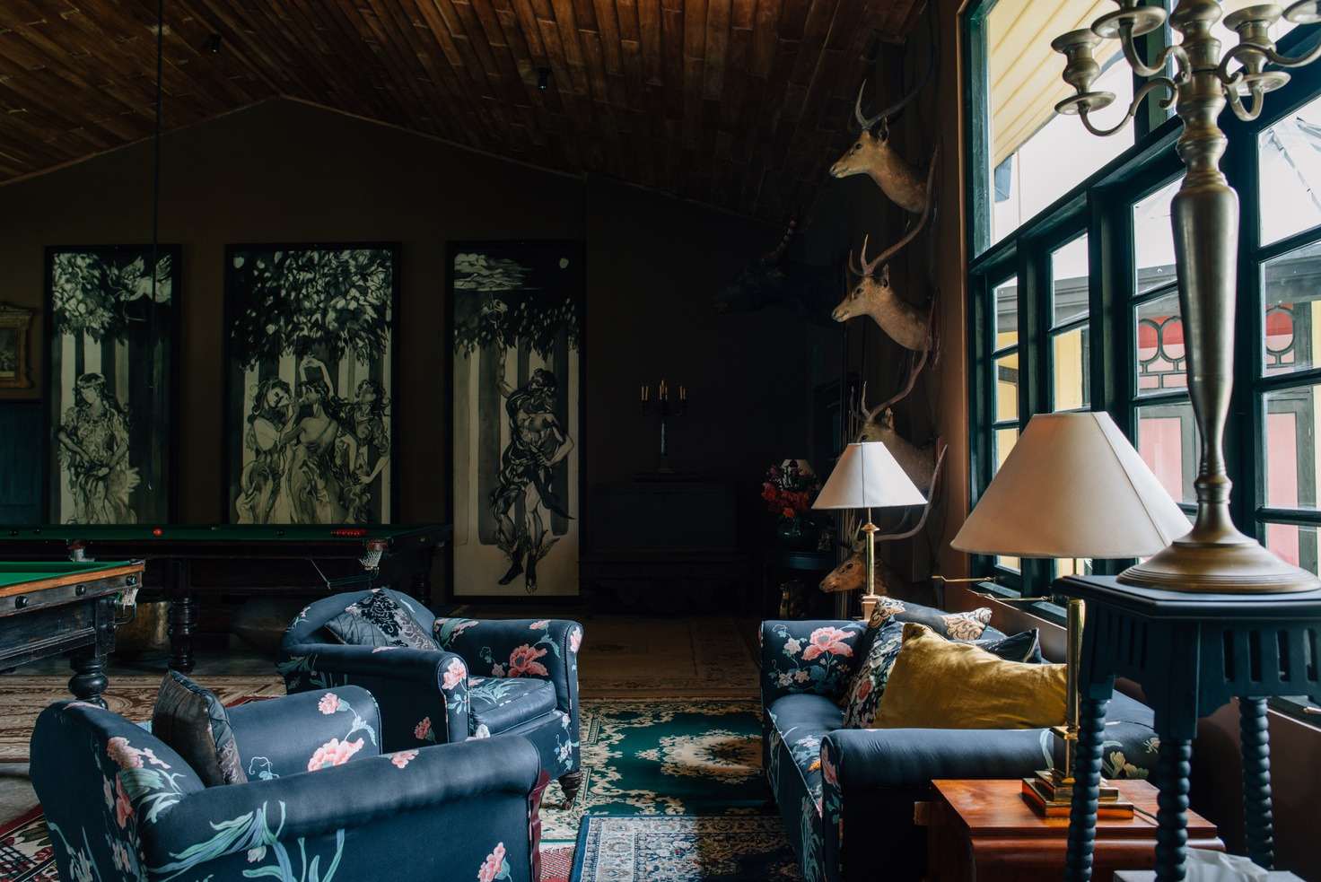 Navy floral armchairs and sofas in the great hall, black-and-white panels behind and stag heads on the wall.