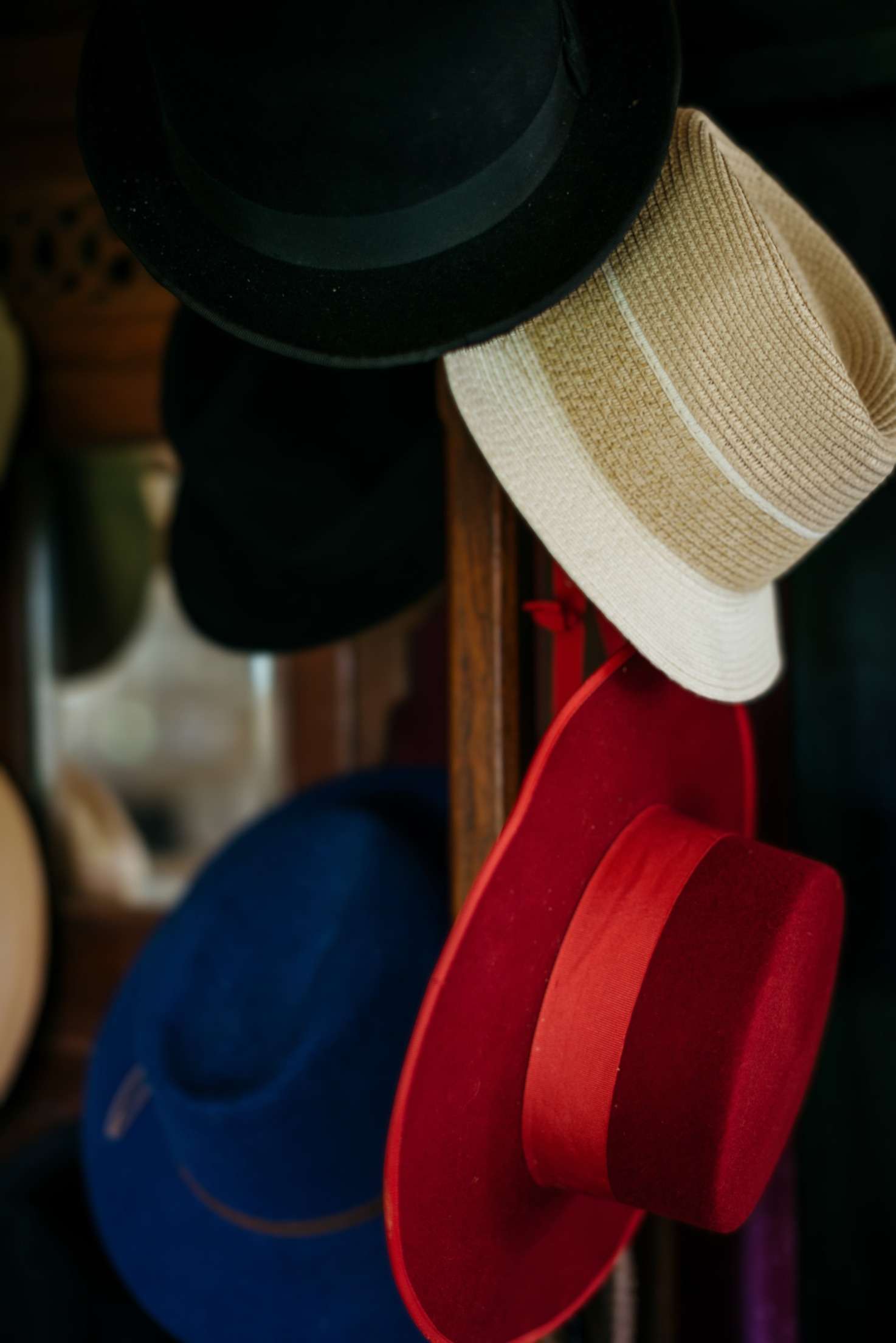 Hats on a wooden stand: a black felt, a straw hat and a red cordobés hat.