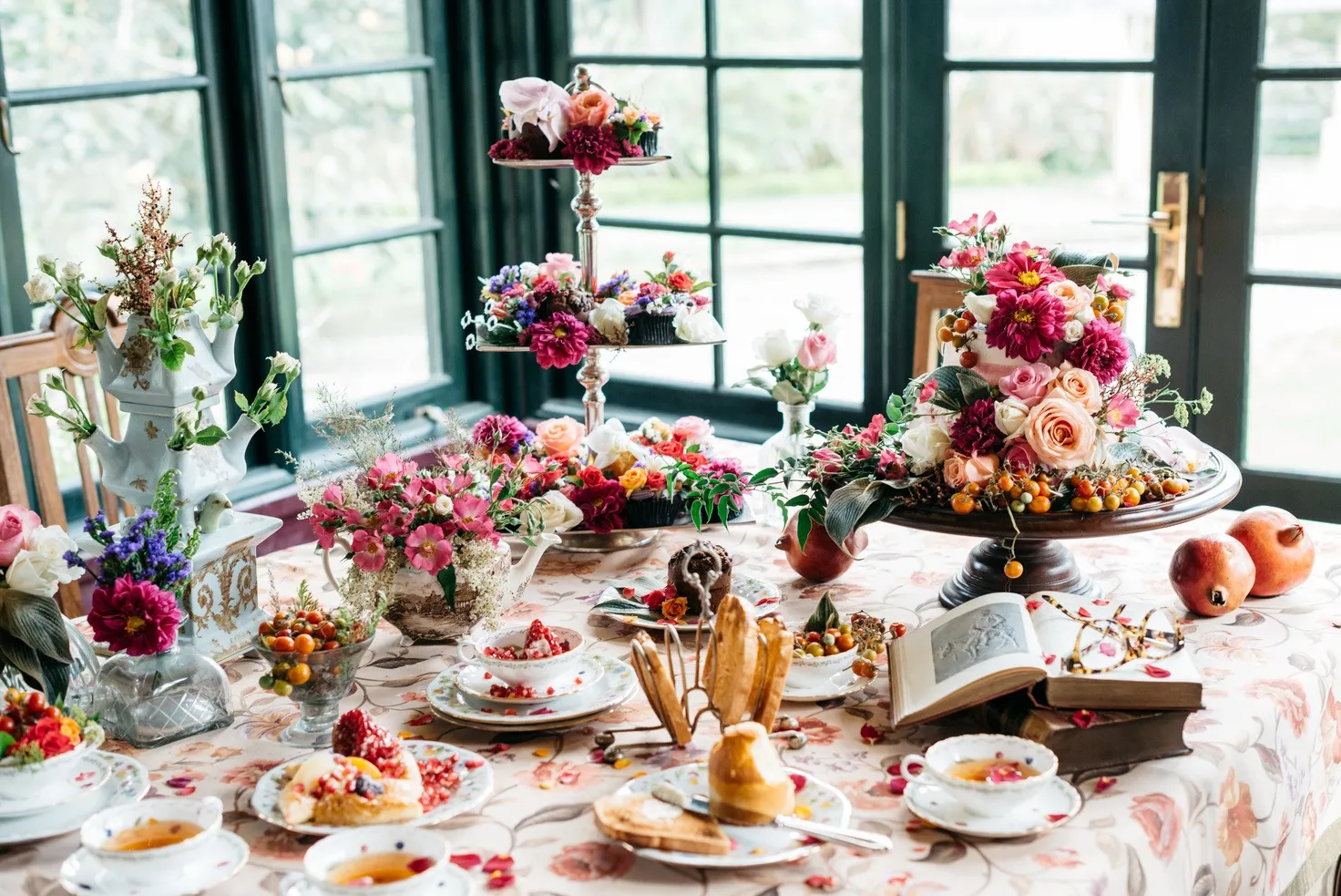A high tea table crowded with flowers and cakes.