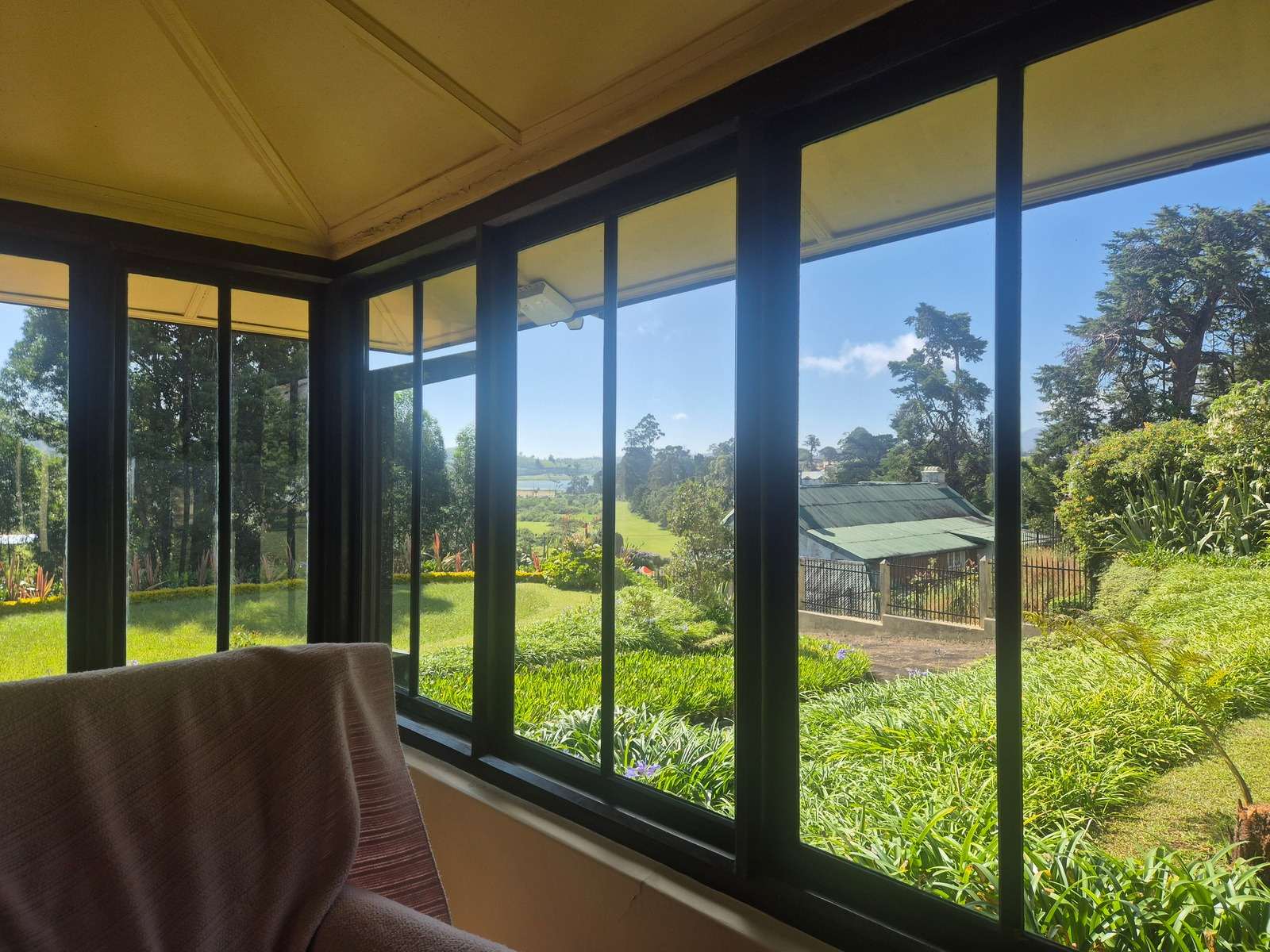 A bedroom window looking out over the garden to green hills.